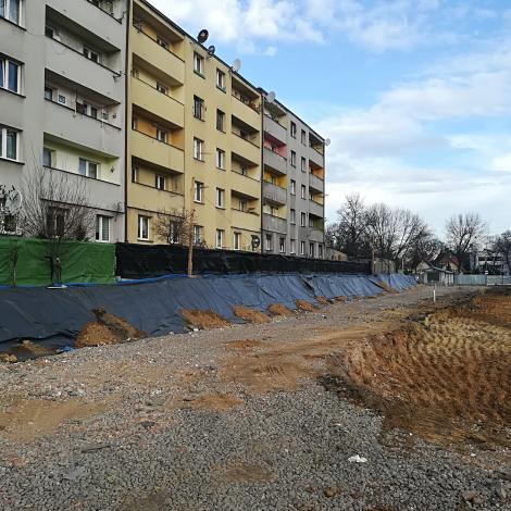  Luty 2020 ogrodzony rozkopany plac budowy na tle bloku mieszkalnego