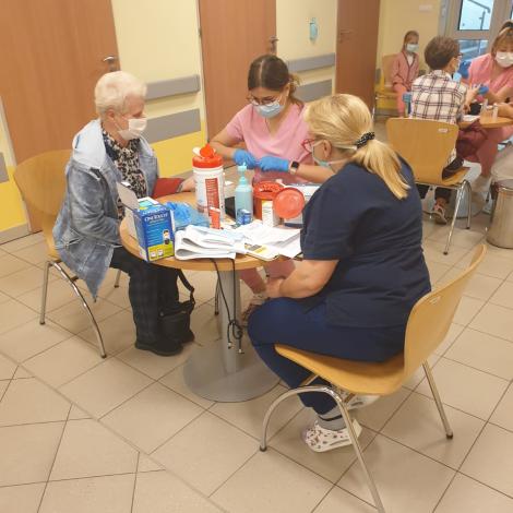 pacjenci siedzący przy stolikach podczas mierzenia poziomu cukru