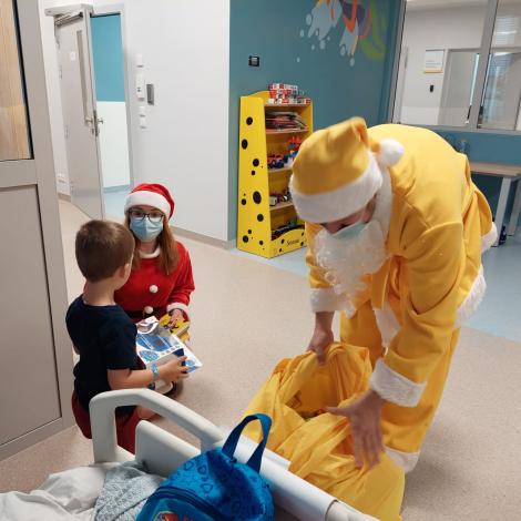 Mikołaj i Mikołajka wręczająca prezent małemu pacjentowi 