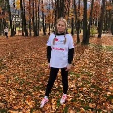 Młoda dziewczyna stojąca w lesie na liściach w koszulce Tak dla Transplantacji